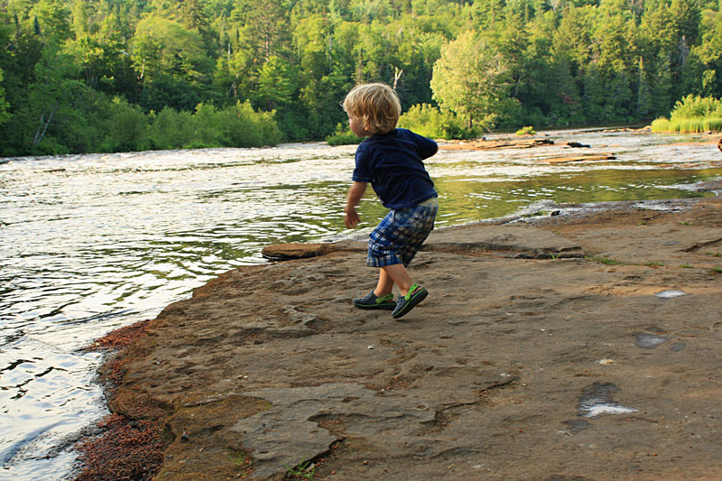 throwing rock into the river below the falls