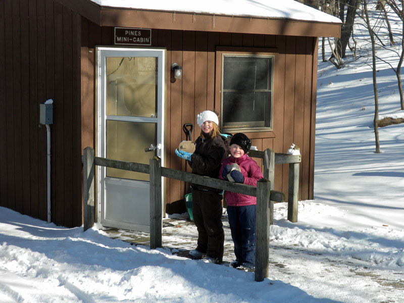 the girls outside the mini camper cabin in ludington state park