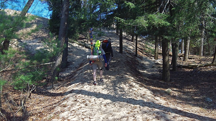 climbing the dune with packs in Ludington State Park